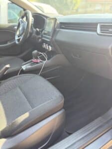 Intérieur d'une voiture moderne, vue du siège passager avant, affichant le tableau de bord, écran tactile central, levier de vitesse et frein à main.