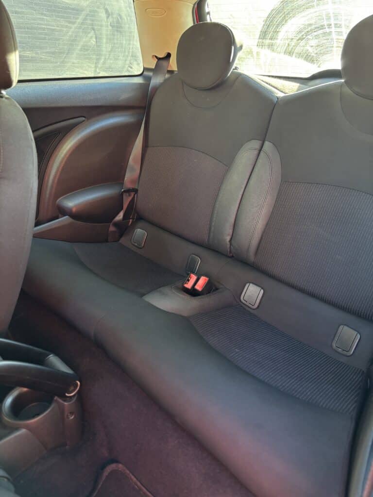 Sièges arrière noirs en tissu et cuir d'une Mini Cooper avec fixations ISOFIX et ceintures de sécurité.