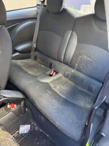 Sièges arrière de voiture noirs très sales couverts de taches de moisissure et de débris alimentaires.
