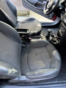 Sièges de Mini Cooper noirs avec taches de moisissure blanches sur le tissu et le cuir du côté conducteur.